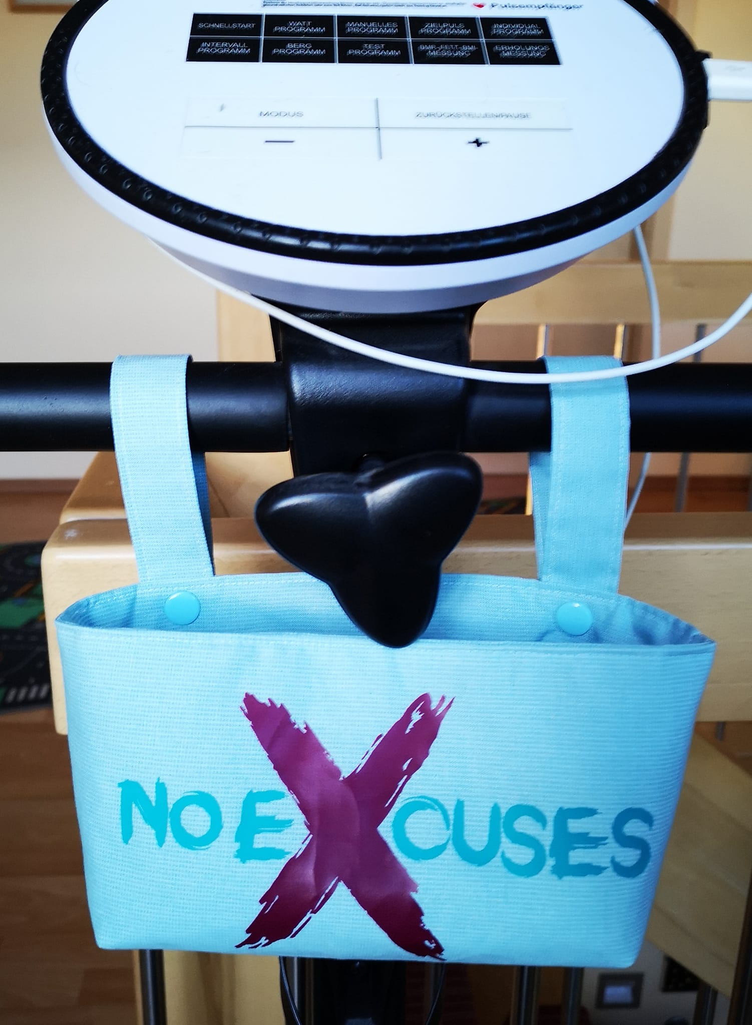 Praktische Tasche mit dem Motiv 'No Excuses' von easy-sticks, angebracht an einem Fitnessgerät.