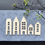 Fein gestaltete Holzhäuser in verschiedenen Formen auf grauem Filz, ideal für kreative DIY Projekte. Häusermotive zum Downloaden von easy-sticks.