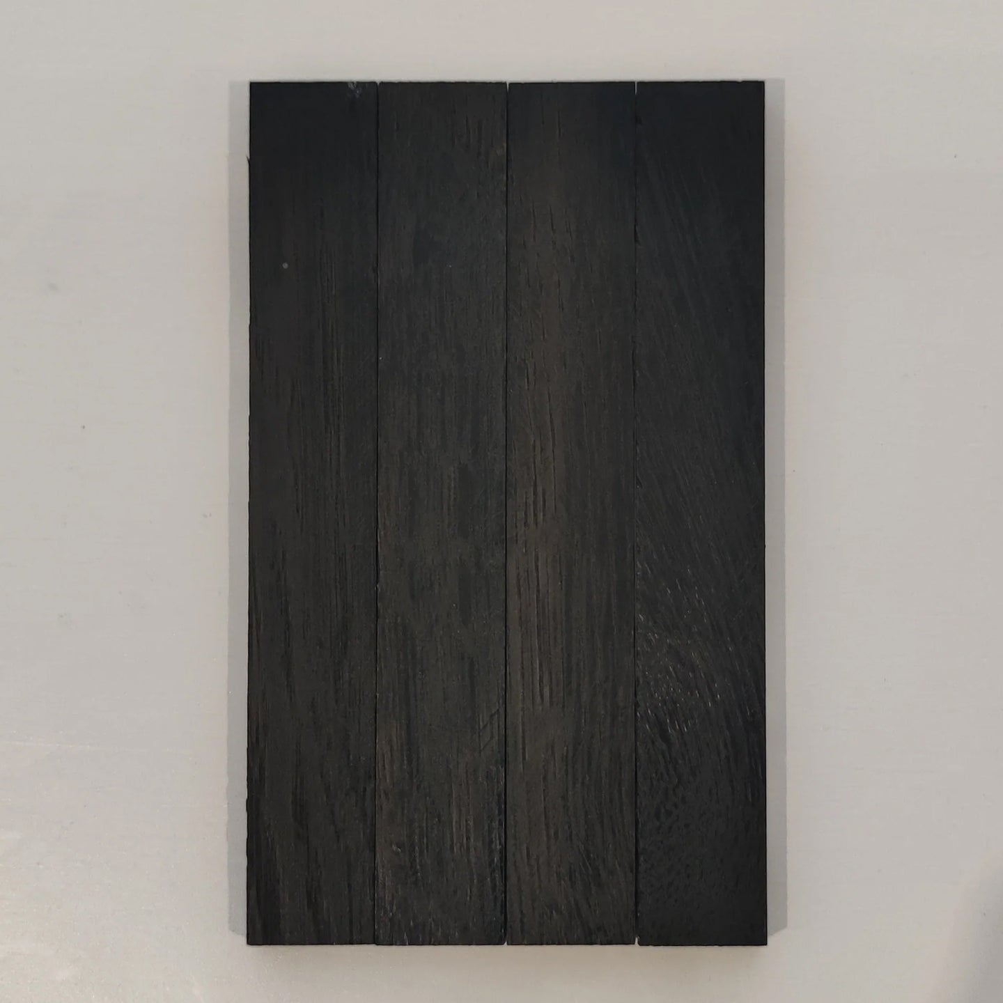 Nahansicht von mit Easy-Sticks Color Schwarz behandeltem Holz, ideal für moderne Inneneinrichtungen und DIY-Projekte.