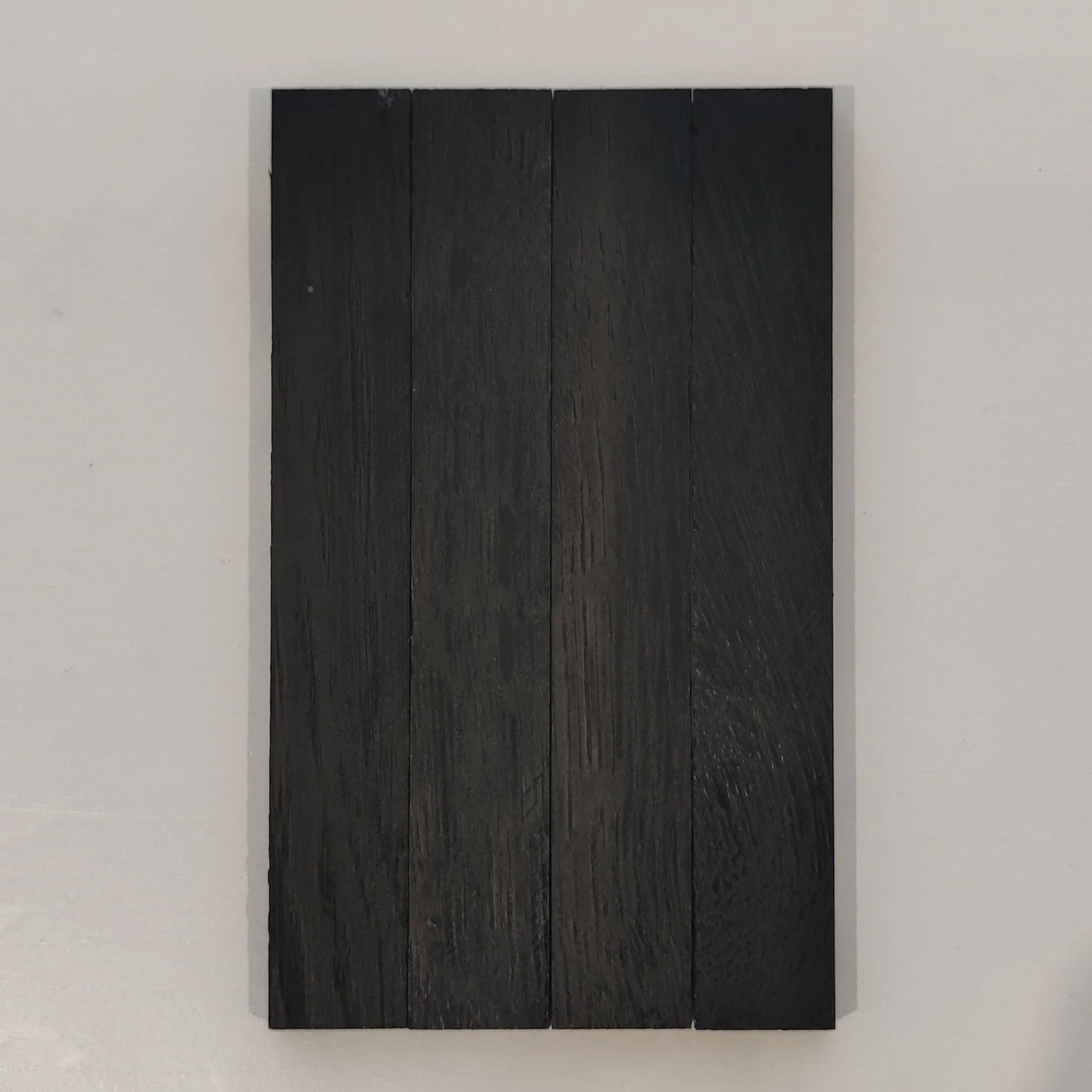 Nahansicht von mit Easy-Sticks Color Schwarz behandeltem Holz, ideal für moderne Inneneinrichtungen und DIY-Projekte.