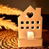 Ein eleganter Teelichthalter von Easy-Sticks, der in Form eines Hauses mit Herz gestaltet ist, strahlt ein sanftes Licht aus und schafft eine gemütliche Stimmung im Raum.