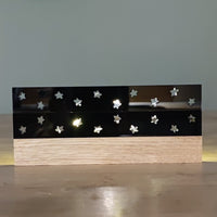 Dekorative Easy-Sticks Acrylplatte in Schwarz mit sichtbaren Sternen und einer eleganten Holzbasis. Die hochglänzende Oberfläche verleiht jedem Raum eine besondere Atmosphäre.