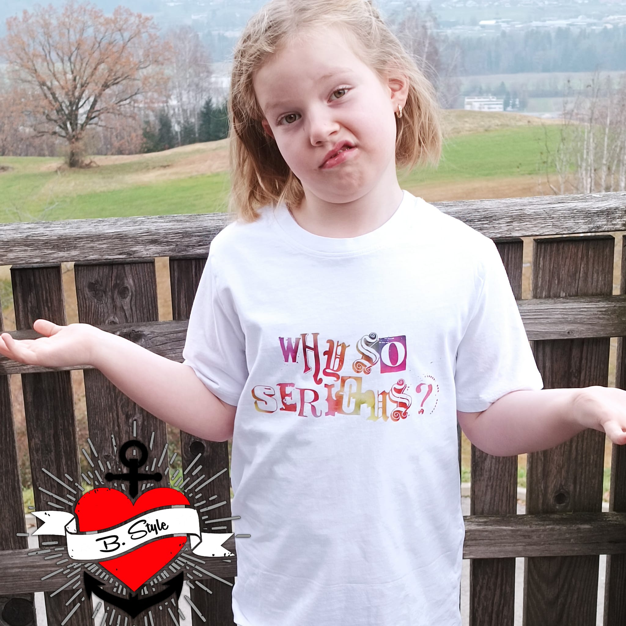 Mädchen zeigt eine witzige Pose in einem weißen T-Shirt mit dem Text "Why so serious?" von easy-sticks, ideal für kreative Projekte.