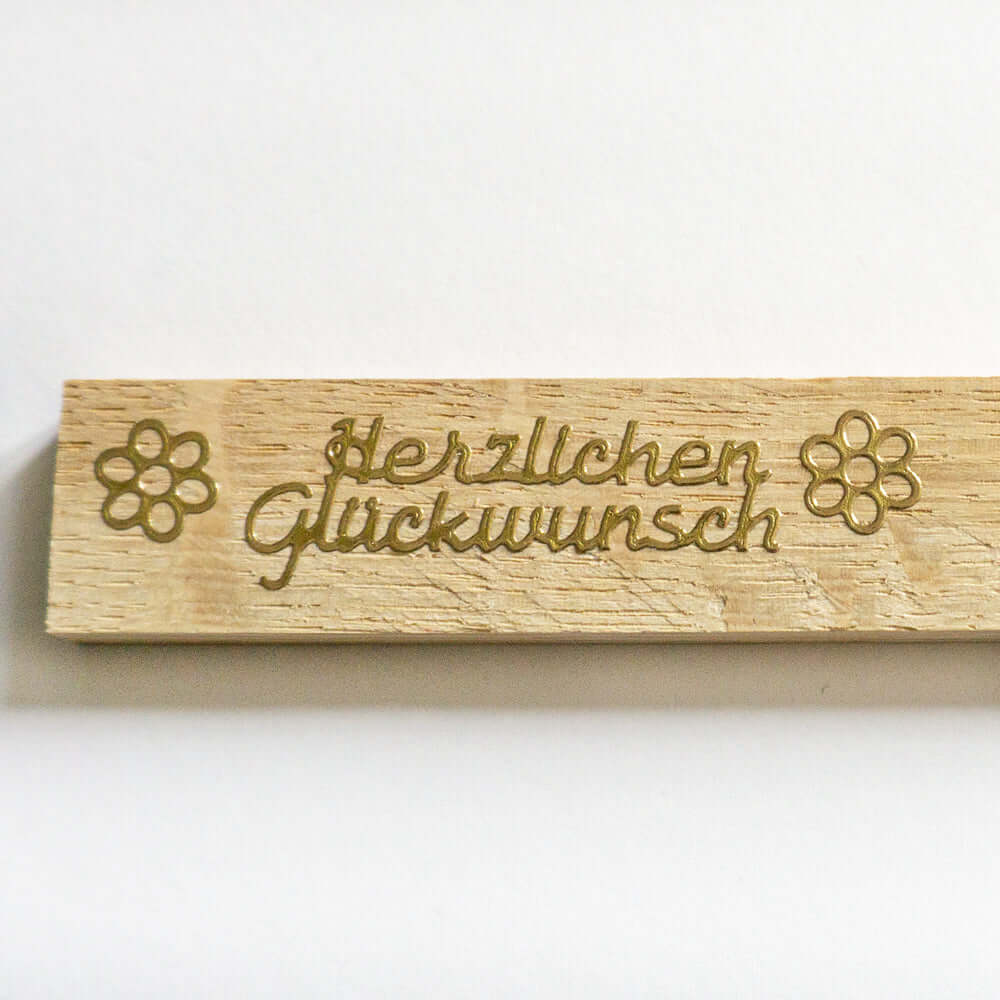 Detailaufnahme eines Holzstickers 'Herzlichen Glückwunsch' in gold, designt von easy-sticks.