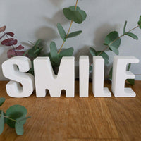 Personalisierte Buchstaben aus Kunstharz von easy-sticks, dargestellt als das Wort 'SMILE' in eleganter weißer Farbgebung, perfekt für kreative Wohnkultur.