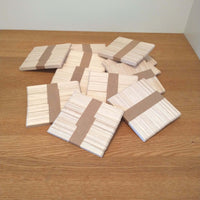 Kreative Anordnung der Easy-Sticks Ice von Easy-Sticks: Mehrere Pakete dünner Bastelsticks aus Holz, ideal für DIY-Projekte auf einem Holztisch.