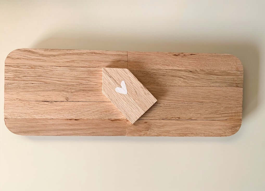 Dekotablett von easy-sticks in der Draufsicht, zeigt ein kleines, herzverziertes Holzhaus auf einer eleganten Grundlage.