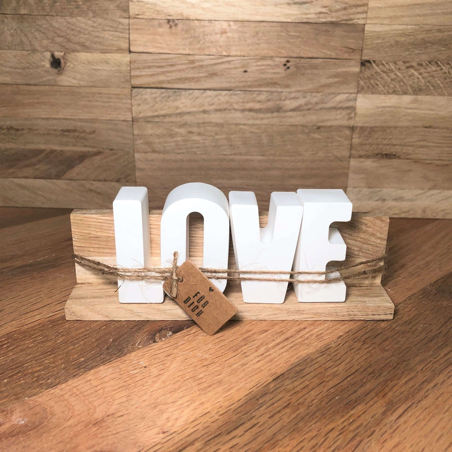 Handgemachte Dekoration Set von easy-sticks: stilvolle LOVE Buchstaben aus Naturholz, präsentiert auf einer Dekoleiste mit einem Geschenkanhänger.