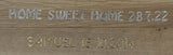 Holzplatte mit eingravierten Buchstaben "HOME SWEET HOME 28.7.22" und "SAMUEL 16.10.2014" in Silber und Gold von easy-sticks.