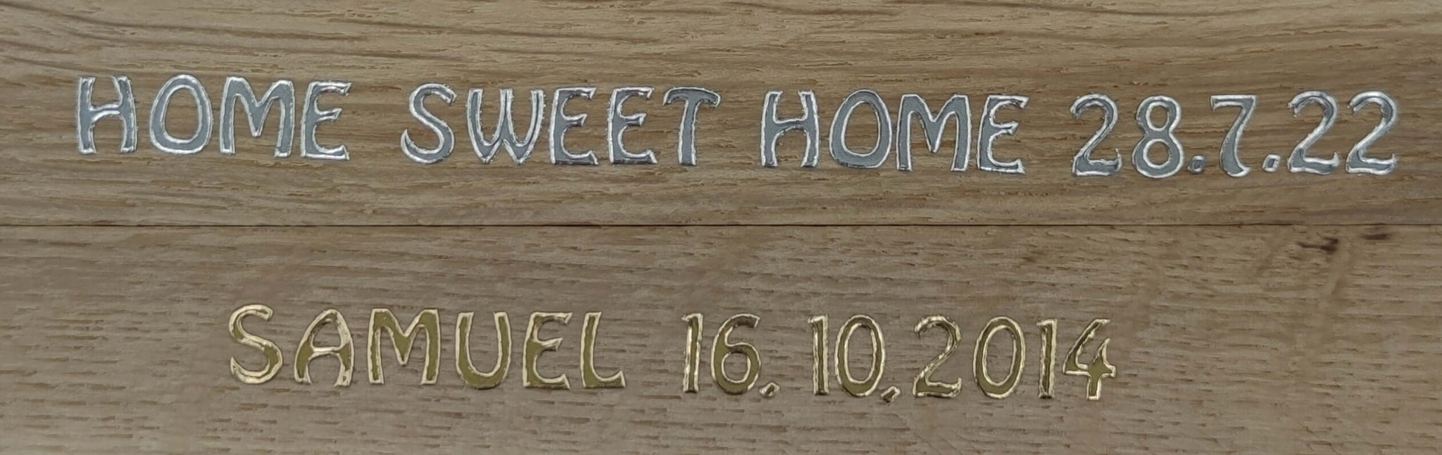 Holzplatte mit eingravierten Buchstaben "HOME SWEET HOME 28.7.22" und "SAMUEL 16.10.2014" in Silber und Gold von easy-sticks.